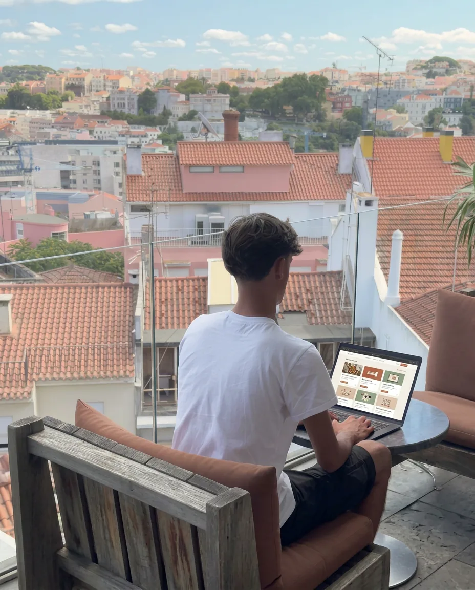 Gaspar de costas a trabalhar no portátil numa varanda com vista sobre os telhados de Lisboa